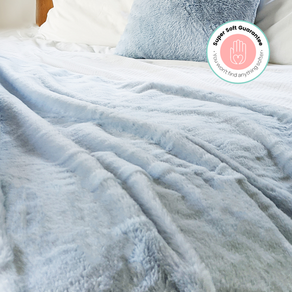 Fluffy blanket on bed in bedroom. Faux Fur in blue. Comfy, cosy home decor products. 